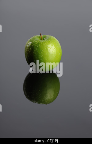 Grüner Apfel mit Reflektion auf grauem Hintergrund Stockfoto