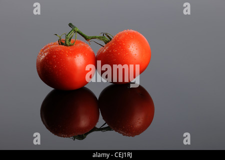 Zwei rote Tomaten auf einem reflektierenden graue Oberfläche Stockfoto