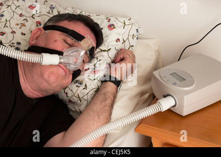 Mann mit einer CPAP-Maske und Maschine verwendet für die Behandlung von Schlafapnoe. Stockfoto