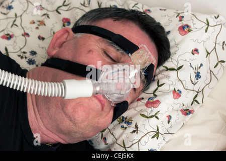 Mann mit einer CPAP-Maske und Maschine verwendet für die Behandlung von Schlafapnoe. Stockfoto