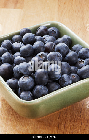 Heidelbeeren in einer grünen Schale auf einem hölzernen Hintergrund Stockfoto