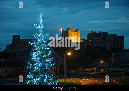Bamburgh Castle in Northumberland, England, UK, aus dem Westen, in der Dämmerung mit einem Weihnachtsbaum im Vordergrund Stockfoto