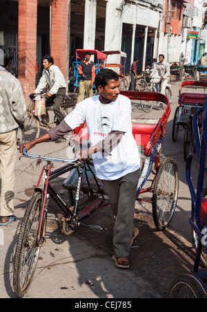 Leben auf der Straße in Alt-Delhi, Indien mit Fahrrad-Rikscha-Wallah in einer belebten Straße in der Sonne Stockfoto