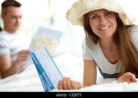 Elegante Dame mit Hut, die Flugtickets beim Blick in die Kamera halten Stockfoto