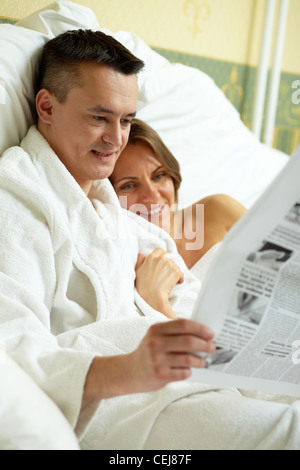 Ehepaar im Bett liegen und Zeitung lesen Stockfoto