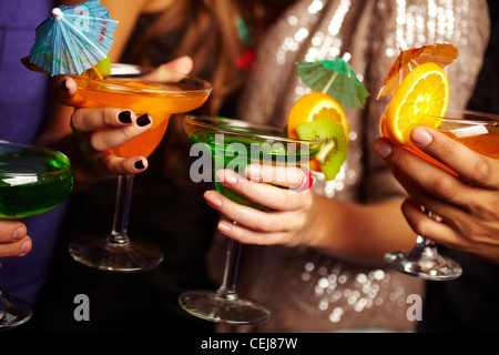 Junge Menschen halten Cocktails, ihre Gesichter werden außerhalb des Bildschirms Stockfoto