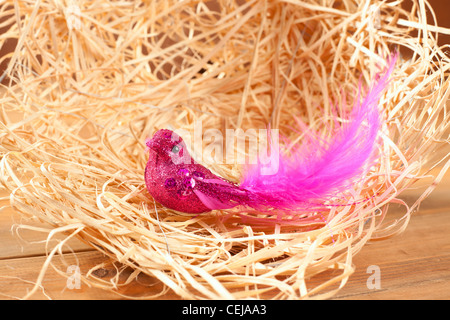 Vogel im Stroh Nest mit rosa Federn und Glitzer-Körper Stockfoto