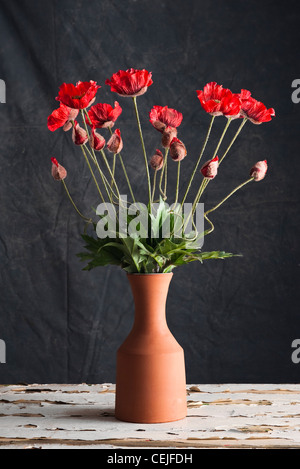 Eine Keramik-Vase mit künstlichen roten Mohnblumen Stockfoto