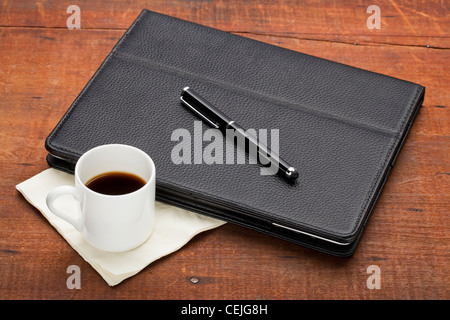 Tablet-Computer im Lederetui mit Stylus-Stift und eine Tasse Espressokaffee auf alte alte Grunge Holz Tisch Stockfoto