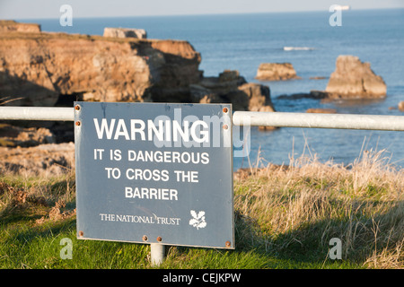 Meer-Stacks und Meer Arch an der nordöstlichen Küste Souter Lighthouse zwischen Newcastle und Sunderland, UK, mit einem Warnhinweis. Stockfoto