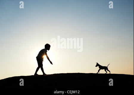 Silhouette der jungen spielen mit seinen Welpen. Indien Stockfoto