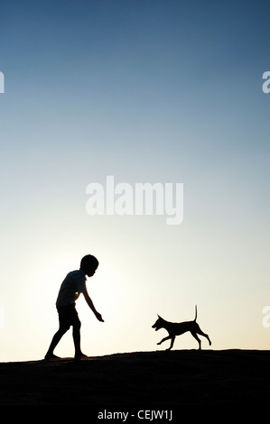 Silhouette der jungen spielen mit seinen Welpen. Indien Stockfoto