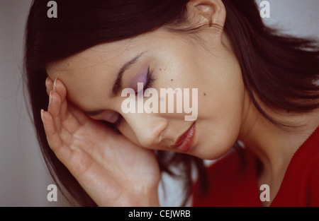 Semi-Profil der weibliche Schulter Länge gerade schwarze Haar geschoben hinter Ohr tragen rote Spitzenkopf in der hand Augen geschlossen Stockfoto