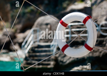 rot weiße Rettungsring auf Draht mit den Schritten zum Meer im Hintergrund Stockfoto