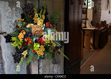 Ein Blumenstrauß im Eingang Kirche bereit für eine Hochzeit und die Gäste durch die Tür Stockfoto