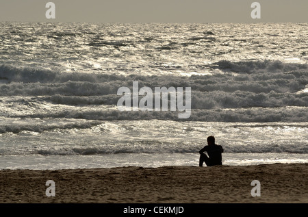 Einsamer Surfer sitzen am Strand, Blick auf See Stockfoto