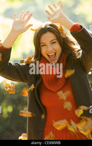 Frauen tragen orange Rollkragen Pullover, verlässt braunen Mantel zu werfen, in Luft, Hände über Kopf Stockfoto