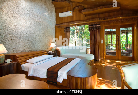 Eine Luxus-Suite in einem tropischen Resort ist auf der Seite eines großen Felsens, der Raum aus Teak, ungewöhnlich wellig Regale gebaut gebaut. Stockfoto