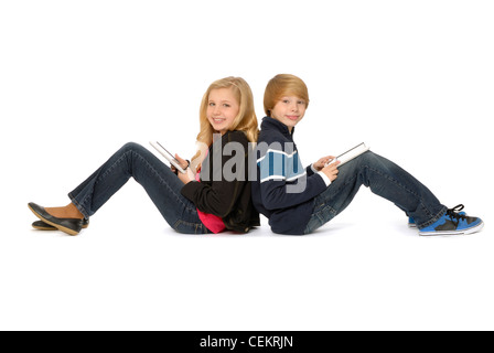 Zehn Jahre altes Mädchen und elf Jahre alten Jungen, Geschwister, sitzen Rücken an Rücken mit Tablet-PCs und lächelnd. Stockfoto