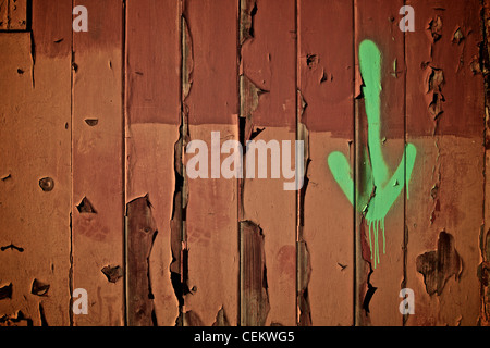 ein grüner Pfeil zeigt nach unten auf eine alte Holztür mit abblätternde Farbe Stockfoto