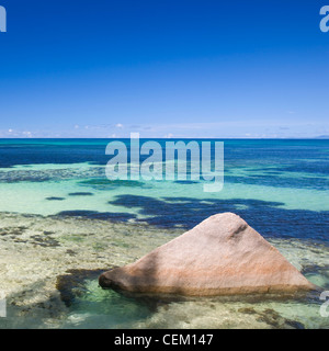 Anse Bois De Rose, Praslin, Seychellen. Blick über das klare Wasser des Indischen Ozeans, Granitblock im Vordergrund. Stockfoto