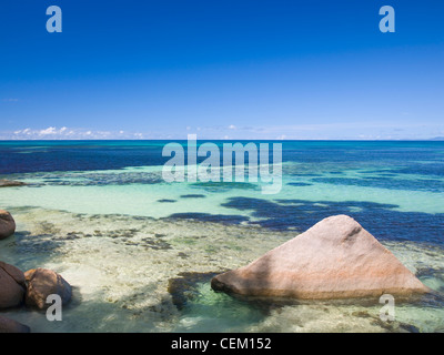 Anse Bois De Rose, Praslin, Seychellen. Blick über das klare Wasser des Indischen Ozeans, Granit Felsen im Vordergrund. Stockfoto