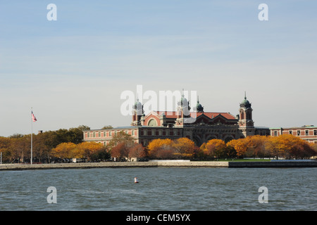 Blauer Himmelsblick von Circle Line Cruise Boot, Herbst Bäume rund um den Hafen von Ellis Island Immigration Museum Building, New York Stockfoto