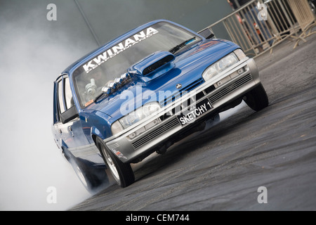 Australischen Holden Commodore-Drag-Rennen Rennwagen einen Burnout zu erwärmen, die hinteren Reifen durchführen. Stockfoto