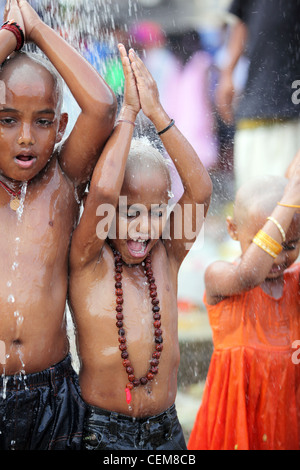 Kinder, die dem Heiligen Duschen während Thaipusam hinduistische Festivals bei Batu Caves in Kuala Lumpur Stockfoto