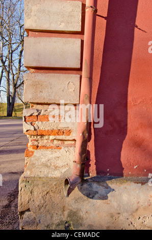 Bröckelnden Ziegel Haus Ecke Wand Closeup und Regenwasser Altleitung. Stockfoto