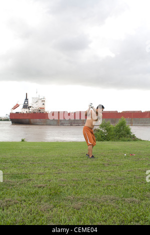 Asiatischer Mann versucht zu schlagen vorbei Fracht / Tanker Schiff mit Golfball in New Orleans Stockfoto