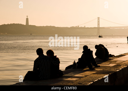 Menschen am Ufer des Tajo Flusses bei Sonnenuntergang. Lissabon, Portugal. Stockfoto