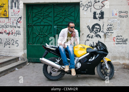 Junger Mann auf dem Motorrad vor revolutionären Graffiti in Zamalek Kairo Ägypten Stockfoto