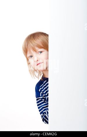 neugieriger Junge mit langen blonden Haaren spähen heraus von hinten eine Tafel auf der Suche Stockfoto