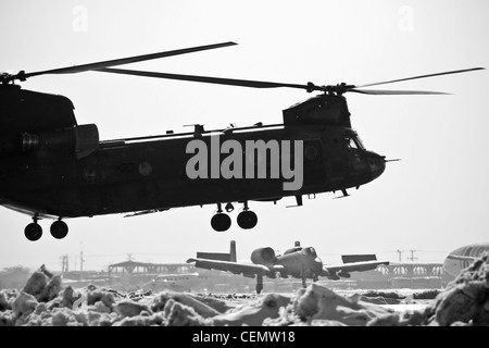 Ein schwerer Hubschrauber der US Army CH-47 Chinook steht für den Start bereit, als eine US Air Force A-10C Thunderbolt II am 16. Februar 2012 auf dem Bagram Air Field, Afghanistan, landet. Stockfoto