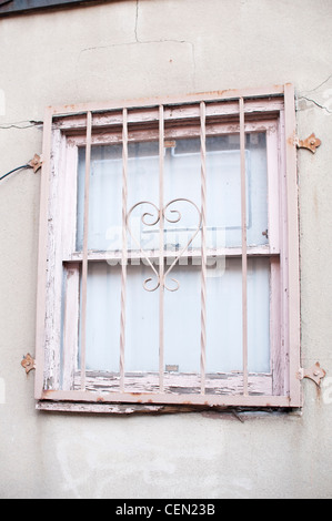 Ein Fenster in einer Gasse in Hoboken, NJ, USA. Das Fenster ist durch rosa Metallstangen geschützt, darunter eine Herzform im Zentrum. Stockfoto