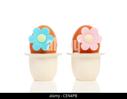 Zwei Hühnereier in Halter mit Blumen auf weißem Hintergrund Stockfoto