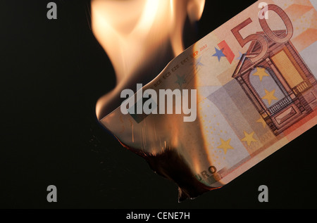 Brennendes Geld auf schwarzem Hintergrund Stockfoto