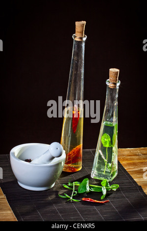 Mörser und Stößel neben Olivenöl-Flaschen Stockfoto