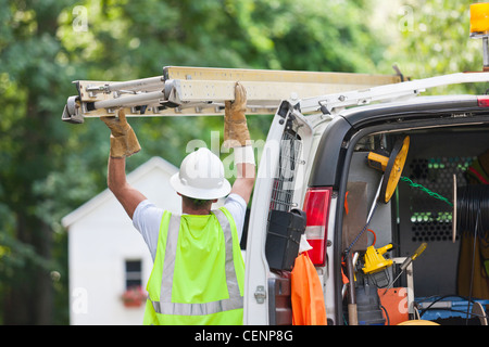 Kommunikation-Arbeiter eine Leiter auf einen LKW geladen Stockfoto