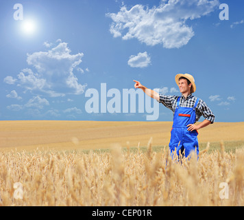 Ein junger Bauer zeigt in einem Weizenfeld Stockfoto