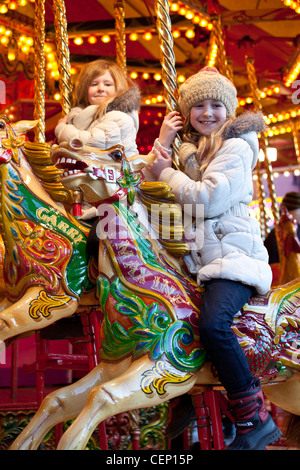 Kinder auf Merry Go Round Messegelände fahren. Stockfoto