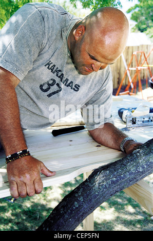 FORBuild ein Baumhaus Schritt männlichen Einführung ein speziell geformtes Stück Holz, um den Baumstamm gehen Stockfoto