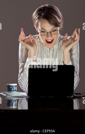 Junge erfolgreiche Frau voller Glück vor ihrem laptop Stockfoto