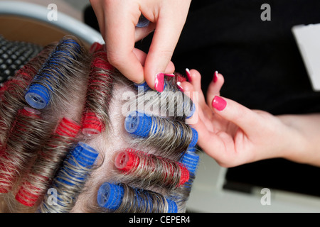 Friseur mit Kunststoff Lockenwickler in einem senior Womens Haar Stockfoto