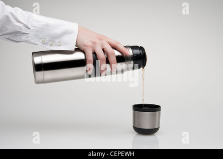 Weibliche Hand Gießen Tee aus der Thermoskanne Stockfoto