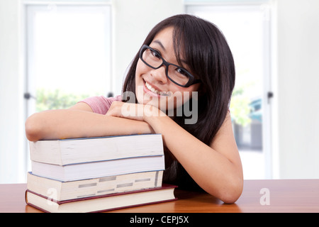 Schönes lächelndes Mädchen in einem Klassenzimmer mit Buch