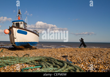 Angelboot/Fischerboot mit Frau zu Fuß am Strand in Dungeness in Kent Stockfoto