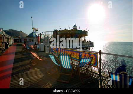 Liegestühle und die Kirmes am Pier von Brighton. Stockfoto