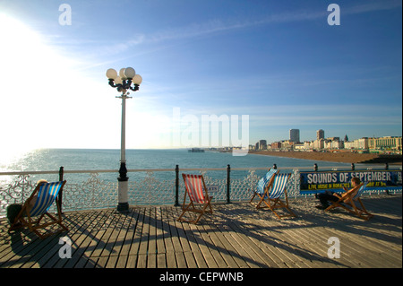 Liegestühle am Pier von Brighton Blick über den Ärmelkanal und die Brighton Seafront. Stockfoto